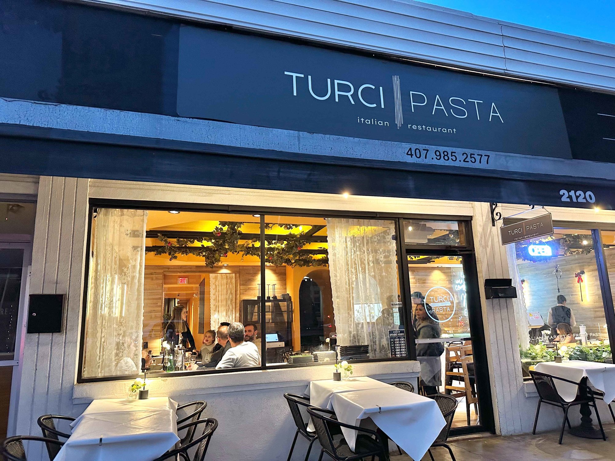front of turci pasta building with glass windows and a black sign